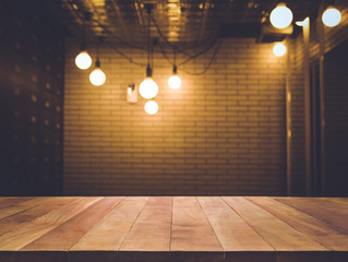 Wall Mural - Wood table top on blurred of counter cafe shop with light bulb background.