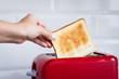 Red toaster with toasted bread for breakfast inside. Hands Girl pulls out ready toasts.