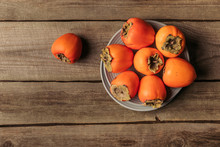 Top View Of Plates With Orange Persimmons On Table