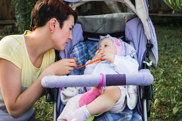 Beautiful young mother with her daughter in stroller in the park