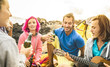 © Mirko Vitali - Hipster friends having fun together at beach camping party - Friendship travel concept with young people travelers playing guitar and drinking bottled beer at summer surf camp - Warm bright filter