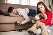 sad daughter sitting with teddy bear while drunk father sleeping on sofa
