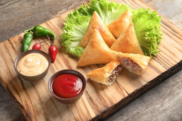 Sticker - Wooden board with delicious meat samosas on table