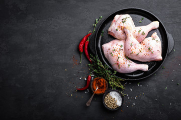 Canvas Print - Raw chicken quarters, legs in a pan on a dark background. Top view.