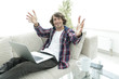 © ASDF - happy guy with a laptop sitting on the sofa and greeting with outstretched hands.