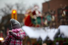 Young Girl On Fathers Shoulders Watching Santa Claus On His Sleigh In A Parade