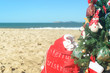 Christmas tree and red Santa bag of presents at the beach