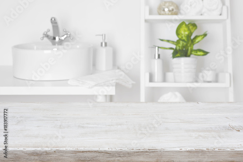 Fotografía Wooden table in front of blurred white bathroom shelves background