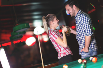 Happy couple drinking beer and playing snooker