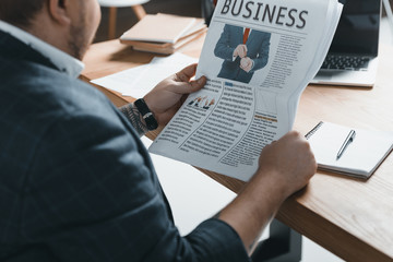 Wall Mural - cropped view of overweight businessman reading business newspaper at workplace