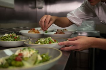 Female chef garnishing appetizer plates at order station