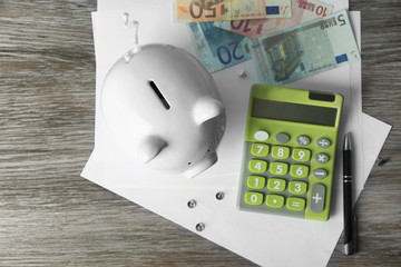 Sticker - Piggy bank with calculator on wooden background