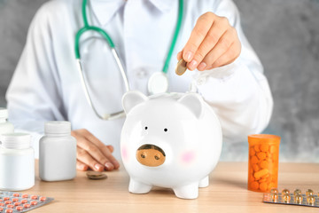 Poster - Doctor putting coin into piggy bank. Health care concept