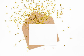 Styled desk with envelope, blank card and golden confetti isolated on a white background. Flat lay. Mockup template. View from above