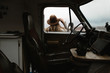 © Nicole Mason/Stocksy - woman standing outside of van window looking out into landscape