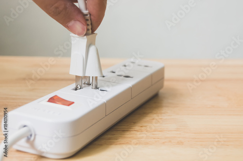 Fotografía Hand of male or female unplugged plug into socket to save energy, Reduce energy