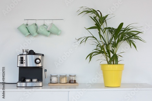 Fotografía Coffeemaker, pot plant and mugs hanging on hook