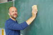 © contrastwerkstatt - lehrer wischt die tafel im klassenzimmer