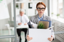 Sad Young Manager Holding Box With Her Things While Leaving Work After Talk With Boss