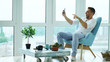 © silverkblack - Young happy man have online video chat using digital tablet computer sitting on balcony in modern loft apartment
