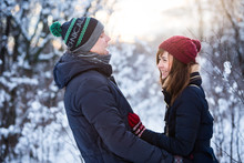 Young Beautiful Couple Having Fun In The Snow Covered Forest Park. New Year And Winter Clothes Concept