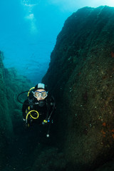 woman scuba diving over rocks in the Mediterranean Sea