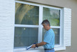 © Michael O'Keene - Homeowner caulking window with a caulk gun, an important part of weatherproofing homes and houses against rain, wind, hurricanes and storms.