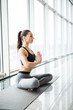© F8  \ Suport Ukraine - Beauty young woman practicing yoga in the lotus position against panoramic windows