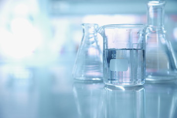 Wall Mural - experiment water in beaker and flask in chemistry science laboratory background