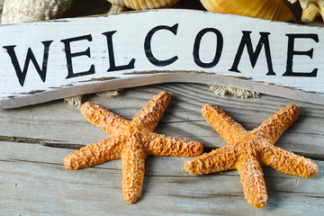 Marine theme. Wooden welcome board. Two orange sea stars. Grey wooden aged background. 