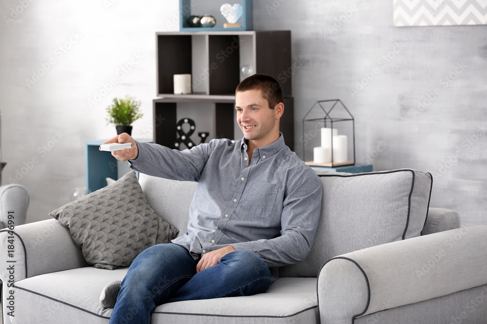 Young man watching TV on sofa at home