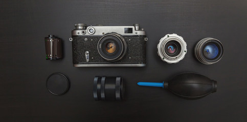 Canvas Print - Vintage Film Camera And Accessories On Black Wooden Background Technology Development Concept. Top View