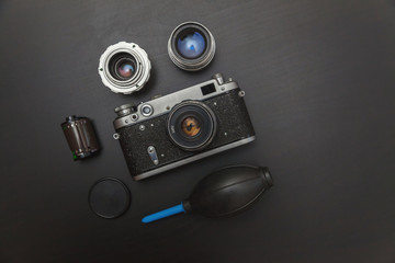 Canvas Print - Vintage Film Camera And Accessories On Black Wooden Background Technology Development Concept. Top View