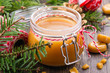 Homemade salted caramel sauce in a glass jar and Christmas decor on wooden background