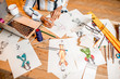 © rh2010 - Fasion designer sketching clothes drawings at the table with tailoring tools and laptop