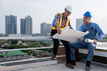 Wall Mural - Engineers and foreman wearing safety helmet hold blueprint talking about construction project working outdoors on the building deck,discussing with project plans.