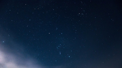 constellation of the orion on a beautiful, night, starry sky with clouds.