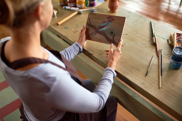 Wall Mural - High angle view portrait of  unrecognizable young woman holding painting enjoying work in art studio, copy space