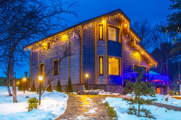 The private house is decorated with New Year's lights. Two storied private house on a winter background.