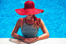 Beautiful European Woman In Red Hat Is Relaxing In The Swimming Pool