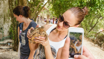 Woman tourist is photographed with small land tortoise