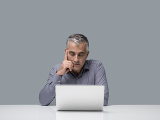 Wall Mural - Pensive businessman working with a laptop