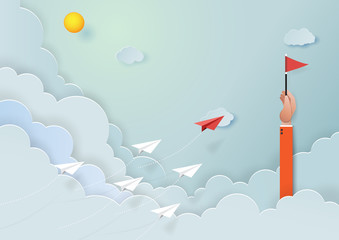 Wall Mural - paper airplanes flying on blue sky to the target of red flag on hand of businessman.paper art style 