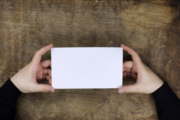 Wall Mural - male hands holding a white blank sheet of paper