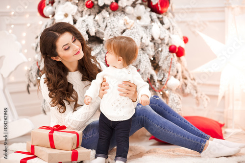 Happy woman holdng baby girl 1 year old wearing whiter