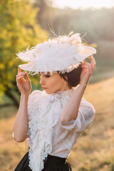 Wall Mural - Exquisite lady in a vintage dress in a beautiful hat walks among the hills, against the background of wild nature. Artistic Photography