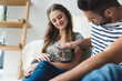 © LIGHTFIELD STUDIOS - happy young couple petting cat at home while sitting on floor