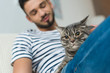 © LIGHTFIELD STUDIOS - close-up shot of young man petting cute tabby cat