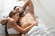 © LIGHTFIELD STUDIOS - top view of young couple embracing in bed in morning