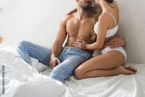 Fotografía cropped shot of young couple in underwear sitting in bed in morning